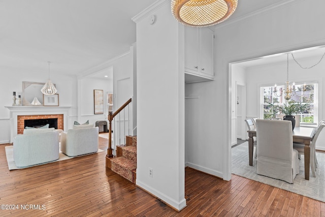 dining space with crown molding, a brick fireplace, dark hardwood / wood-style floors, and a notable chandelier