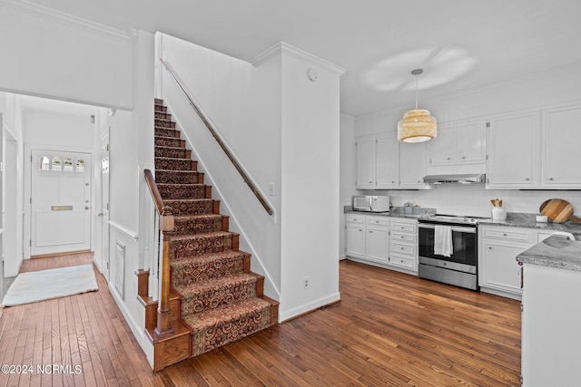 kitchen with dark wood-type flooring, hanging light fixtures, white cabinets, decorative backsplash, and stainless steel range with electric cooktop