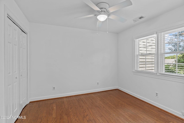 unfurnished bedroom featuring multiple windows, ceiling fan, a closet, and hardwood / wood-style flooring