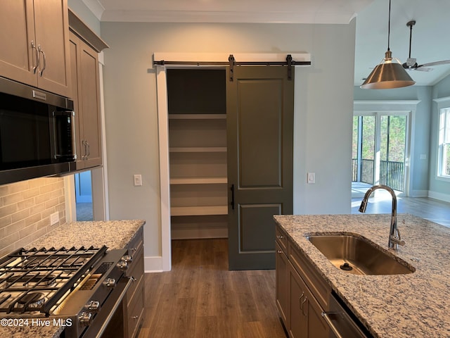 kitchen with decorative backsplash, light stone counters, stainless steel appliances, dark wood-type flooring, and sink