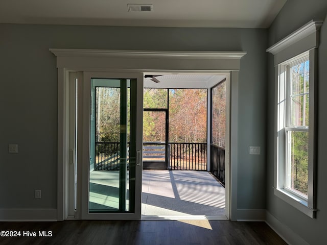 doorway with ceiling fan, dark wood-type flooring, and a healthy amount of sunlight