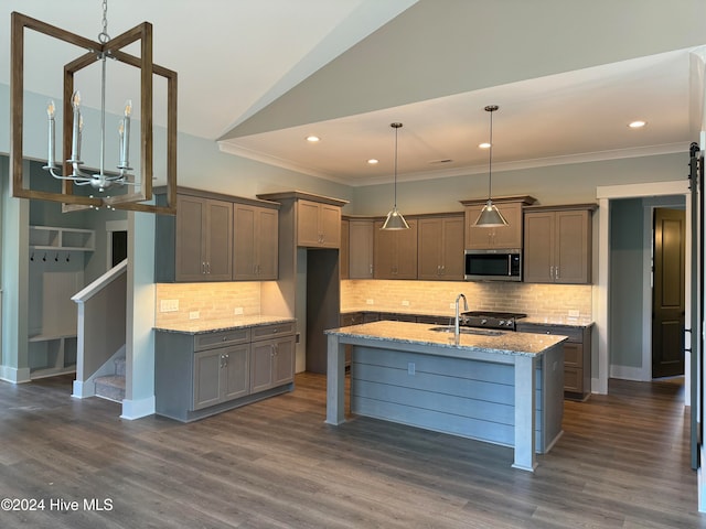 kitchen with light stone countertops, sink, dark wood-type flooring, tasteful backsplash, and decorative light fixtures