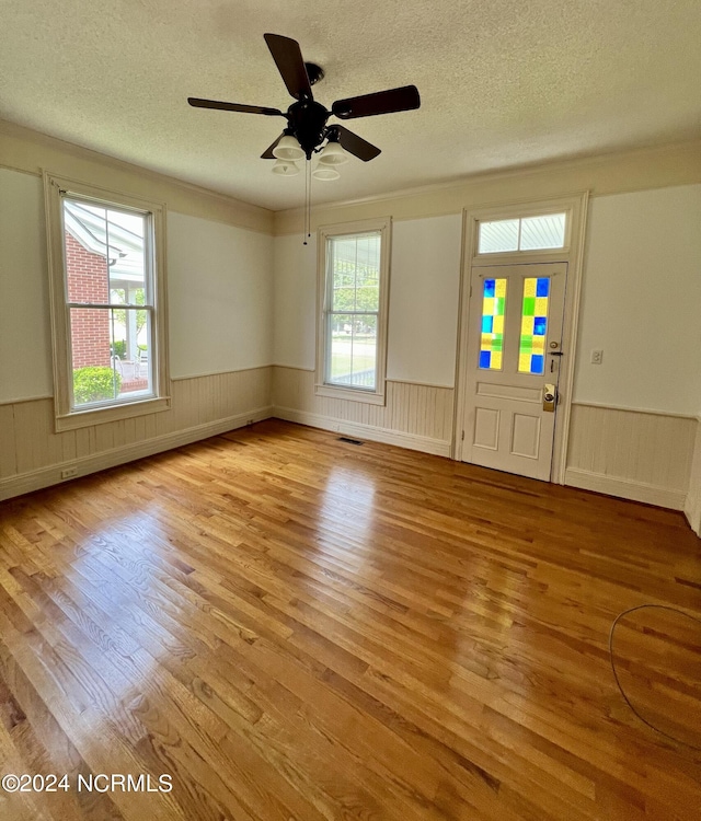 unfurnished room featuring a wealth of natural light, a textured ceiling, ceiling fan, and light hardwood / wood-style floors