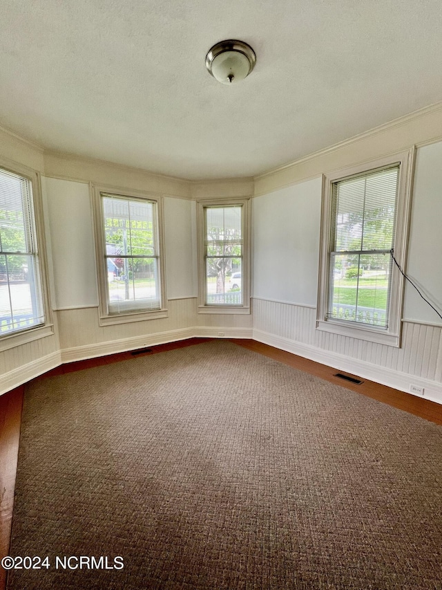 spare room with hardwood / wood-style flooring, a wealth of natural light, and ornamental molding