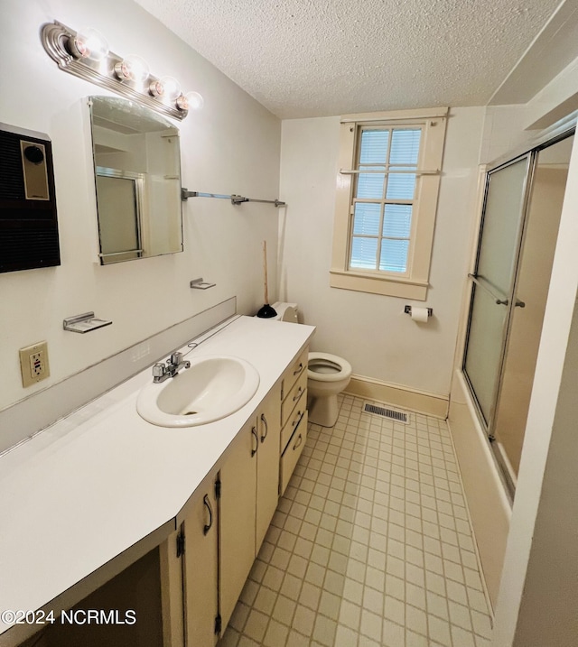 full bathroom featuring tile patterned flooring, shower / bath combination with glass door, a textured ceiling, toilet, and vanity