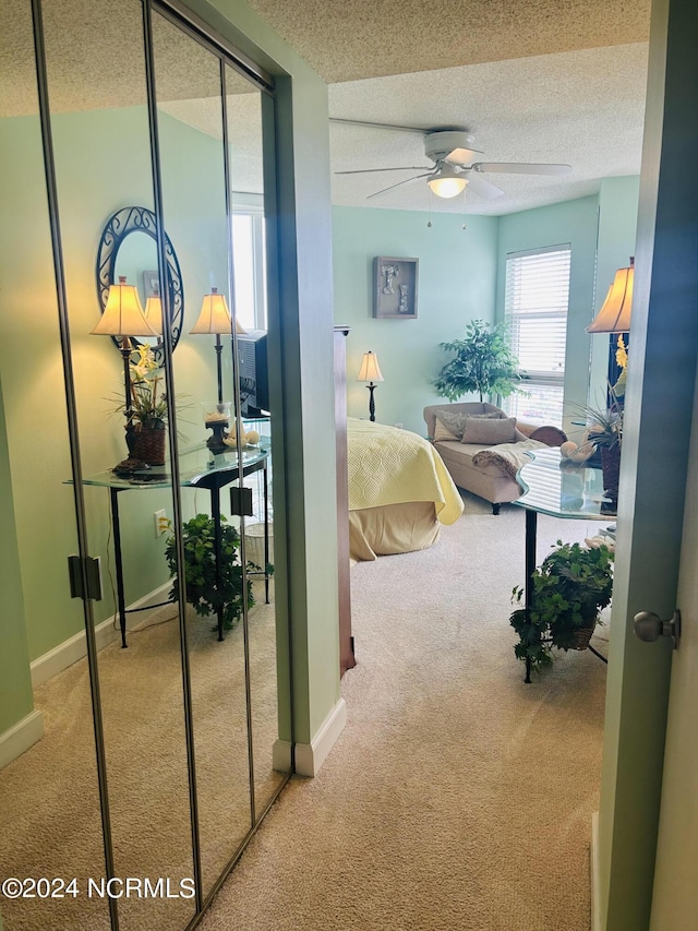 hall with carpet floors, a textured ceiling, and baseboards