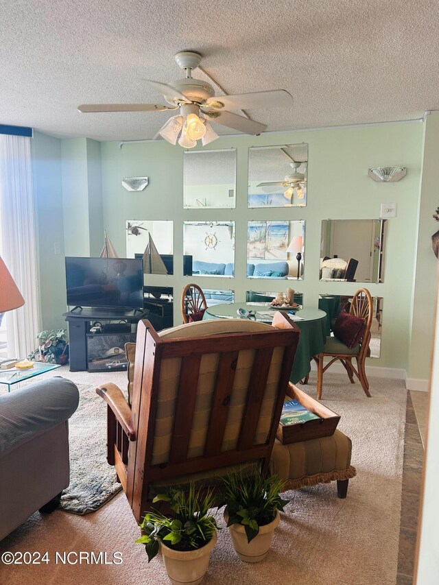 living area with a textured ceiling, carpet, and a ceiling fan