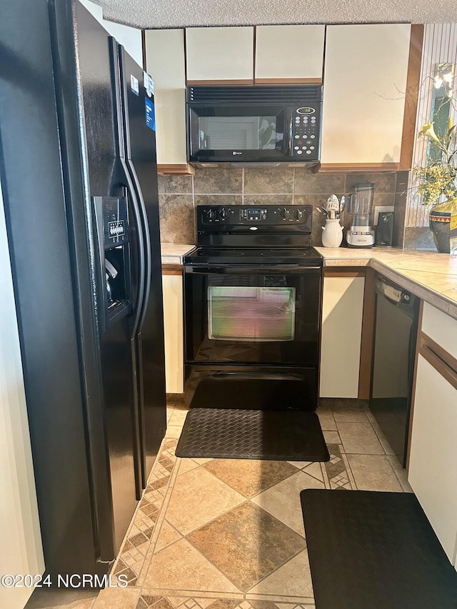 kitchen featuring tasteful backsplash, light countertops, black appliances, and white cabinetry