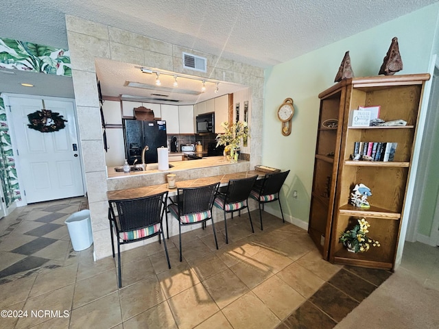 kitchen featuring tasteful backsplash, visible vents, white cabinets, a textured ceiling, and black appliances