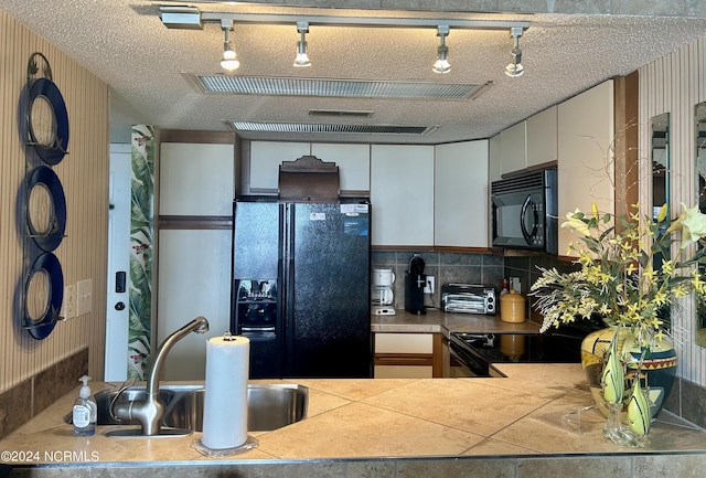 kitchen featuring a textured ceiling, a toaster, a sink, light countertops, and black appliances