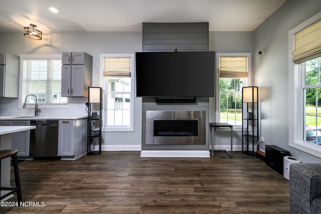 kitchen featuring dishwasher, a tile fireplace, gray cabinets, sink, and dark wood-type flooring