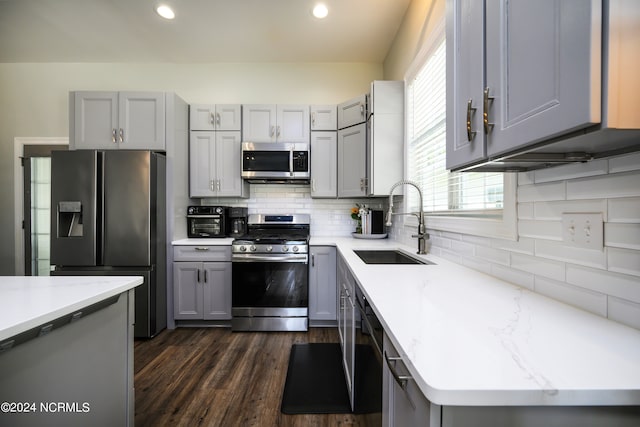 kitchen with gray cabinets, appliances with stainless steel finishes, a healthy amount of sunlight, backsplash, and sink