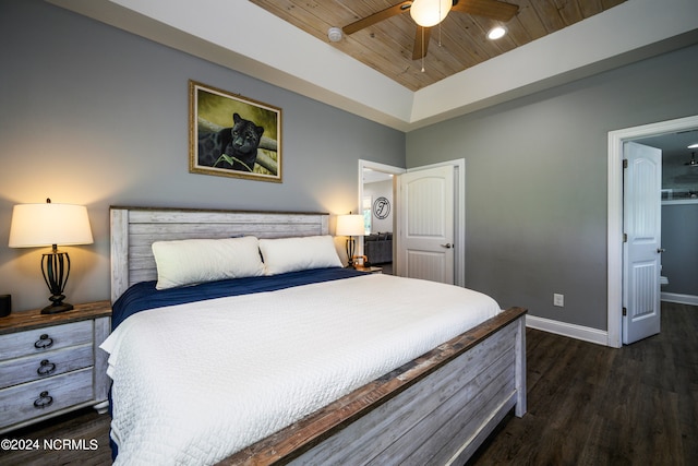 bedroom featuring wood ceiling, ceiling fan, a tray ceiling, ensuite bath, and dark wood-type flooring