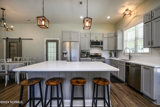 kitchen with decorative light fixtures, a barn door, stainless steel appliances, and a center island