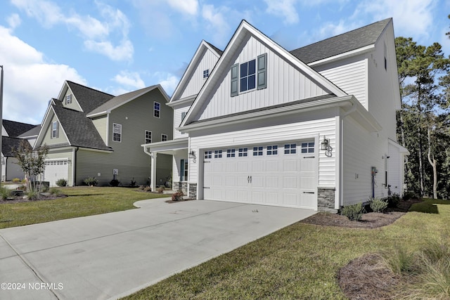 65 Tilloo Cut Way, Hampstead, NC 28443 - view of front of house featuring board and batten siding, driveway, a front yard, an attached garage, and stone siding