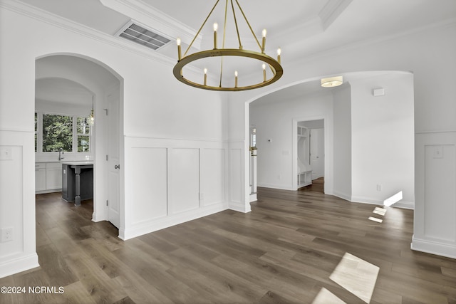 65 Tilloo Cut Way, Hampstead, NC 28443 - unfurnished dining area with a decorative wall, dark wood-style flooring, a chandelier, crown molding, and arched walkways
