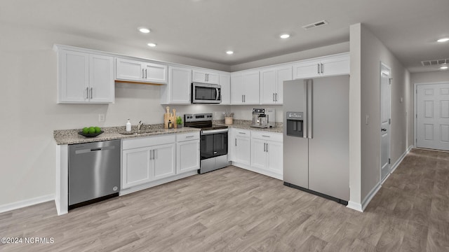 kitchen with light stone countertops, appliances with stainless steel finishes, light hardwood / wood-style flooring, and white cabinetry