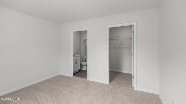 unfurnished bedroom with light carpet, connected bathroom, a spacious closet, and a closet