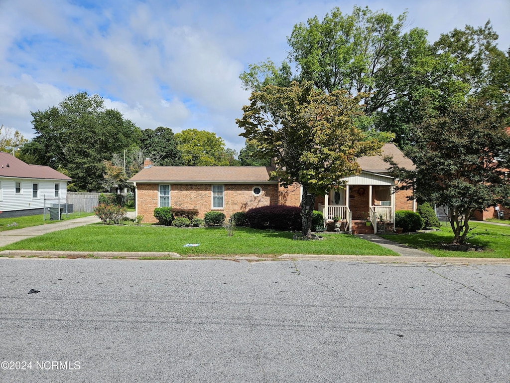 view of front of house featuring a front lawn, central air condition unit, and covered porch