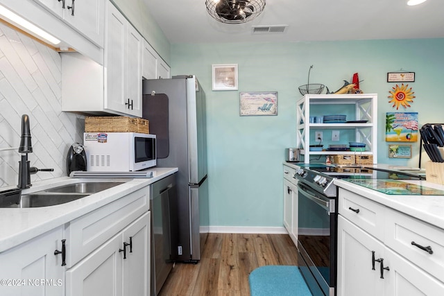 kitchen featuring white cabinetry, tasteful backsplash, stainless steel appliances, hardwood / wood-style floors, and sink