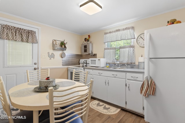 kitchen with white cabinetry, wood-type flooring, white appliances, sink, and backsplash