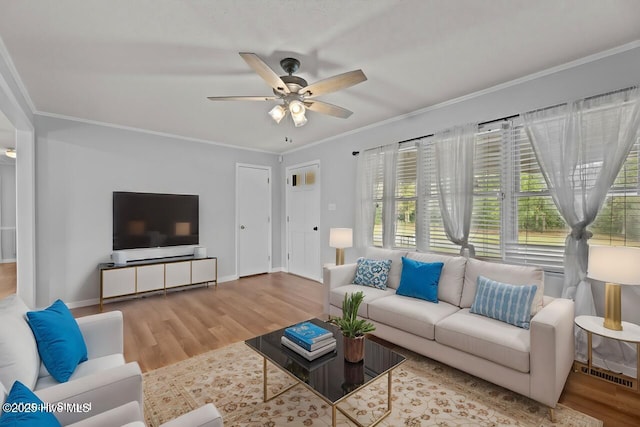 living room featuring ceiling fan, ornamental molding, wood finished floors, and baseboards