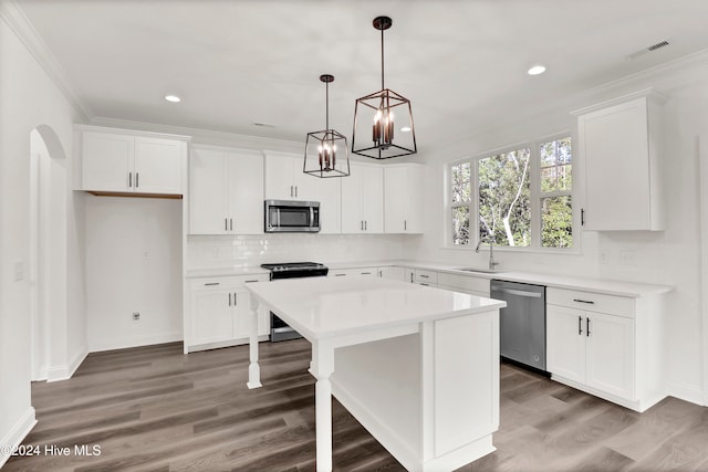 kitchen with stainless steel appliances, decorative light fixtures, white cabinetry, dark hardwood / wood-style floors, and a kitchen island