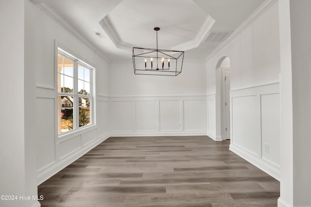 unfurnished dining area featuring a tray ceiling, wood-type flooring, and ornamental molding