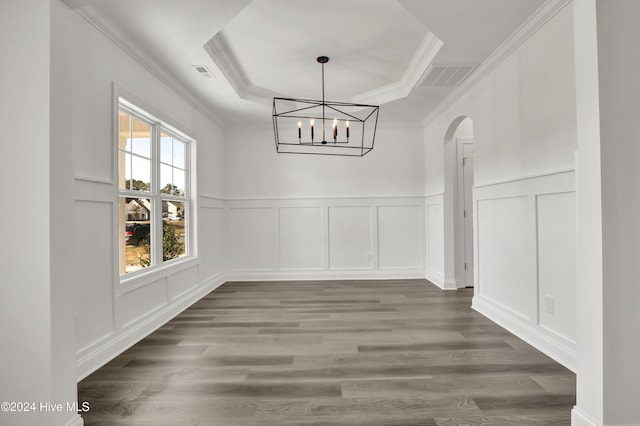 133 Tilloo Cut Way, Hampstead, NC 28443 - unfurnished dining area with a decorative wall, arched walkways, a tray ceiling, wood finished floors, and ornamental molding