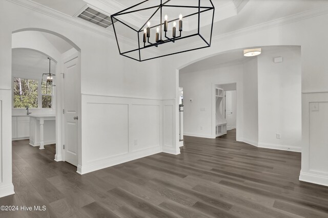 133 Tilloo Cut Way, Hampstead, NC 28443 - unfurnished dining area featuring a decorative wall, arched walkways, dark wood finished floors, a wainscoted wall, and crown molding