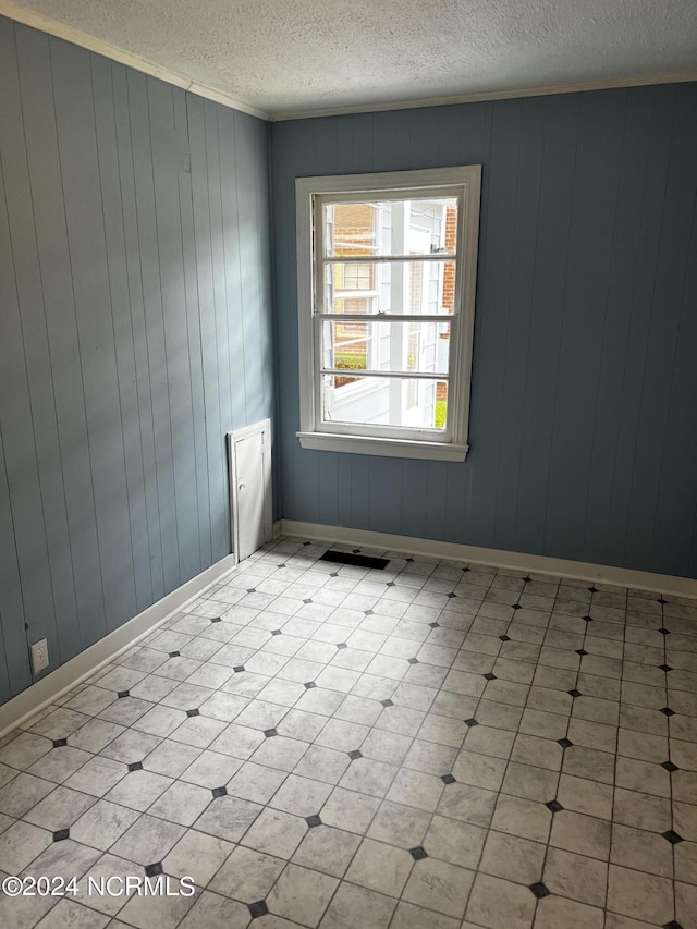 unfurnished room featuring baseboards, a textured ceiling, and ornamental molding