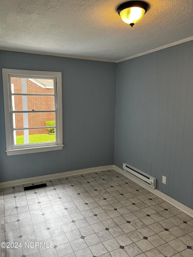 empty room featuring crown molding, a baseboard heating unit, a textured ceiling, and tile patterned floors