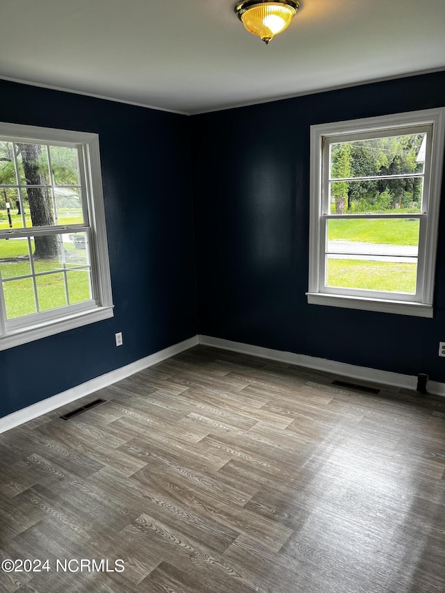 unfurnished room with a healthy amount of sunlight, visible vents, and baseboards