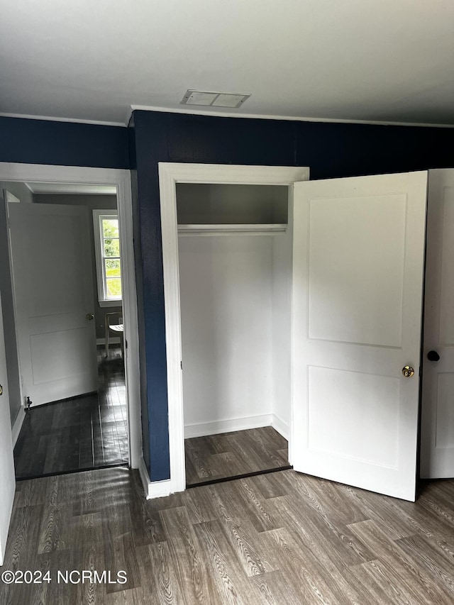 unfurnished bedroom featuring a closet, visible vents, baseboards, and wood finished floors