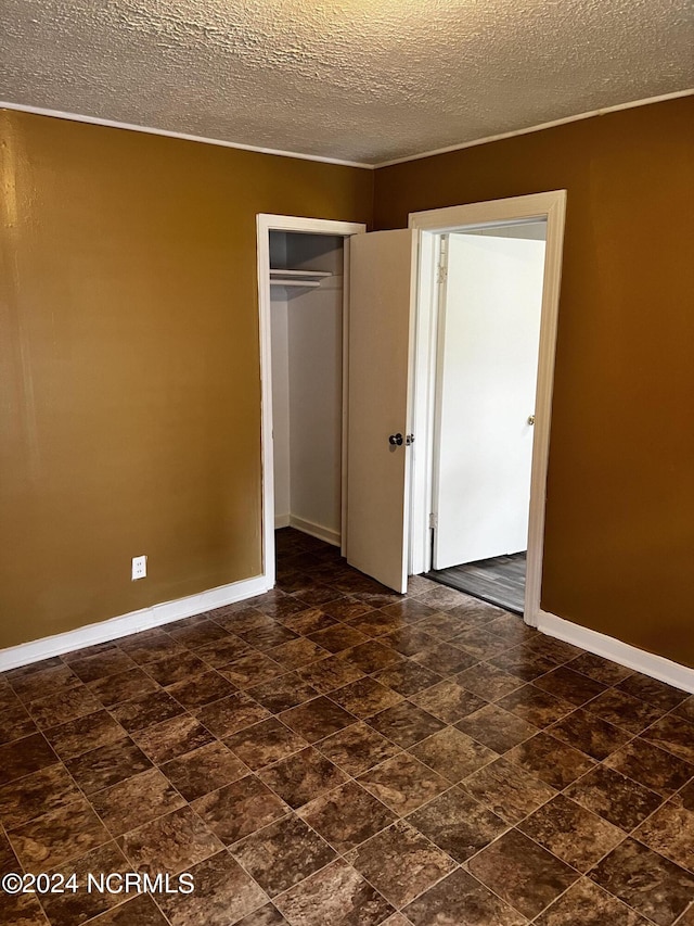 unfurnished bedroom with a closet, a textured ceiling, and baseboards