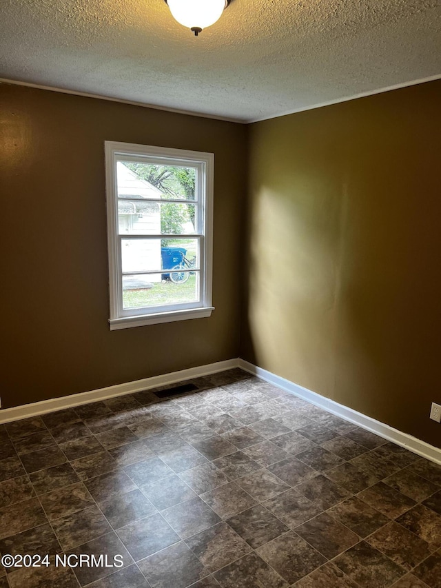 empty room featuring a textured ceiling, visible vents, and baseboards