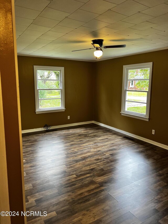 empty room featuring ceiling fan, baseboards, and dark wood finished floors