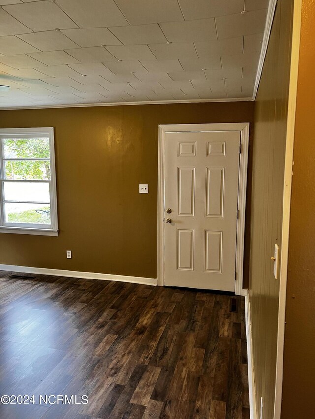 interior space with ornamental molding, dark wood-style flooring, and baseboards