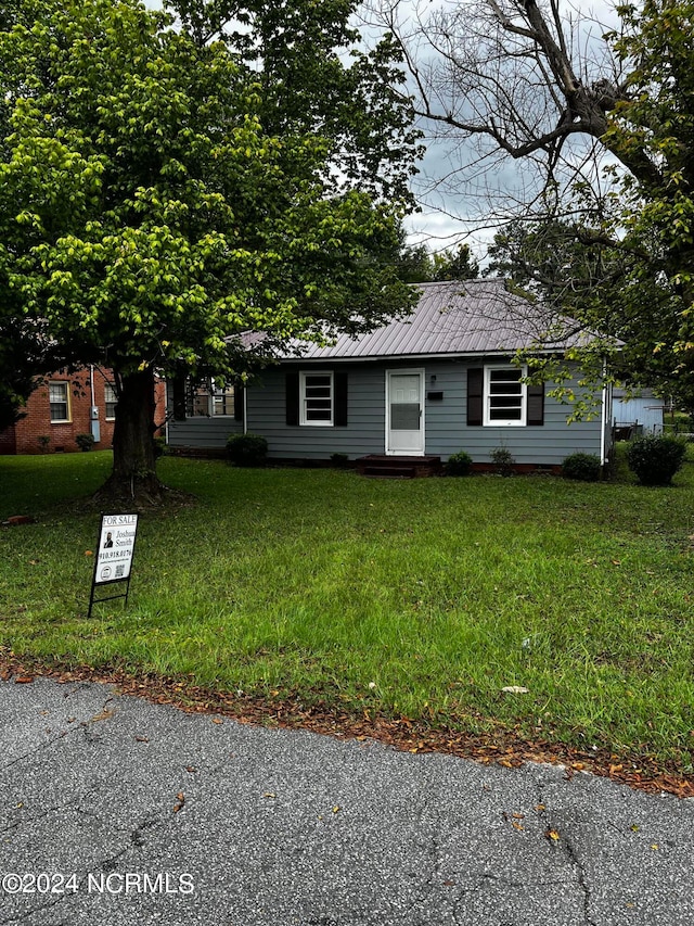 view of front of home featuring metal roof and a front yard