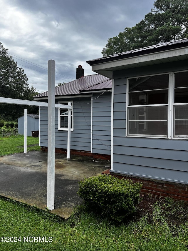 view of home's exterior featuring metal roof, a patio, and a chimney