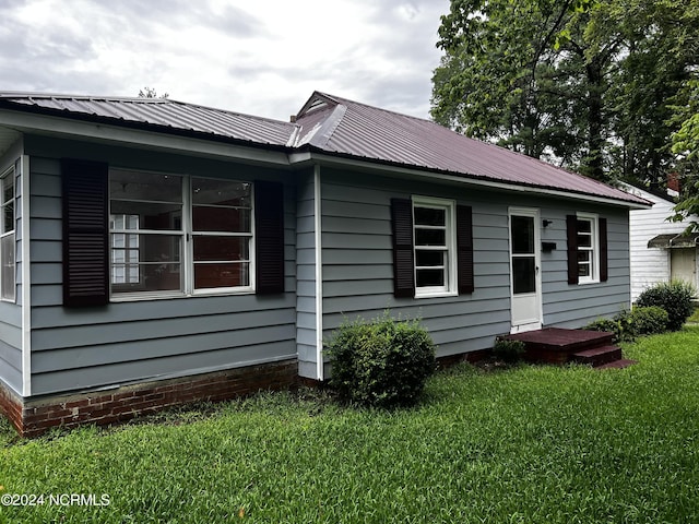 view of home's exterior with metal roof and a yard