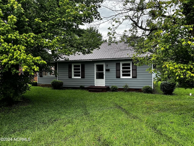 single story home with metal roof and a front yard