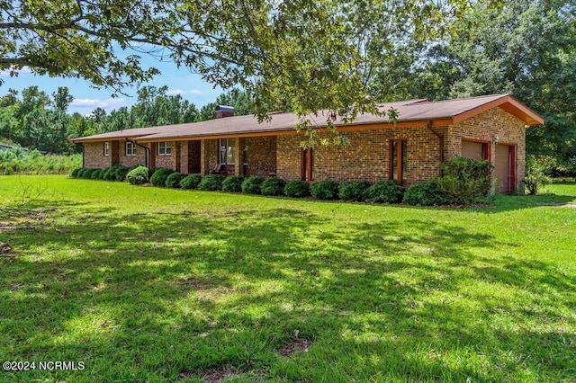 ranch-style house featuring a garage, a front yard, brick siding, and a chimney