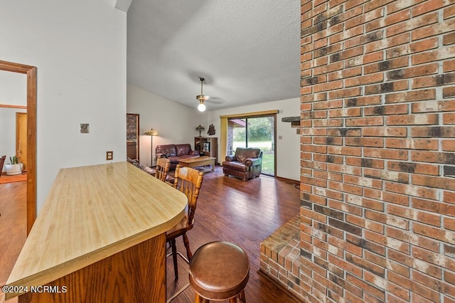 dining area with lofted ceiling, a textured ceiling, wood finished floors, and a ceiling fan