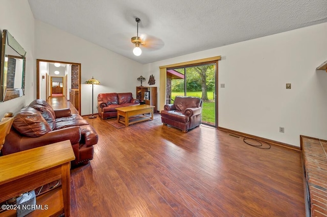 living area with hardwood / wood-style floors, vaulted ceiling, a textured ceiling, ceiling fan, and baseboards