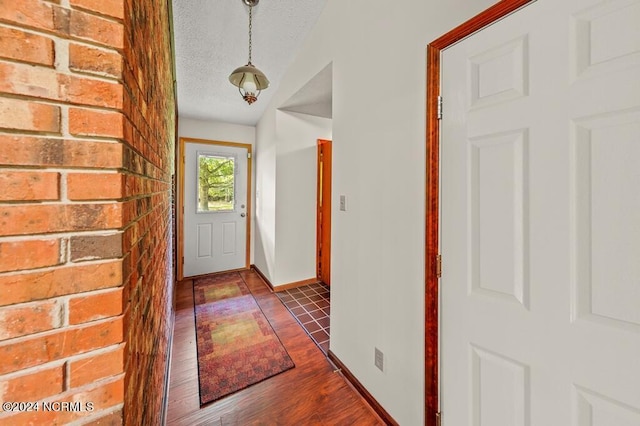 doorway to outside with dark wood finished floors, a textured ceiling, and baseboards