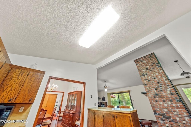 interior space featuring brown cabinetry, vaulted ceiling, a textured ceiling, and light countertops