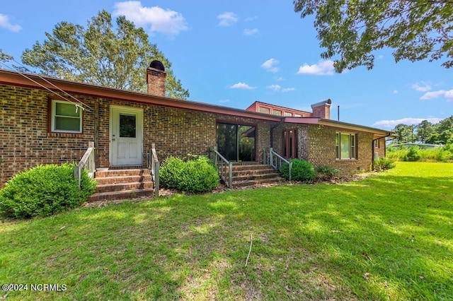 view of front of property with a chimney, a front lawn, and brick siding