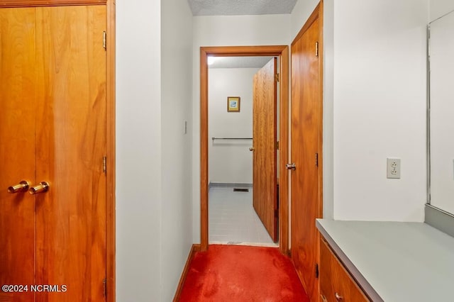 hallway with a textured ceiling and carpet floors