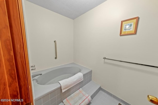 bathroom with a textured ceiling, a bath, and tile patterned floors